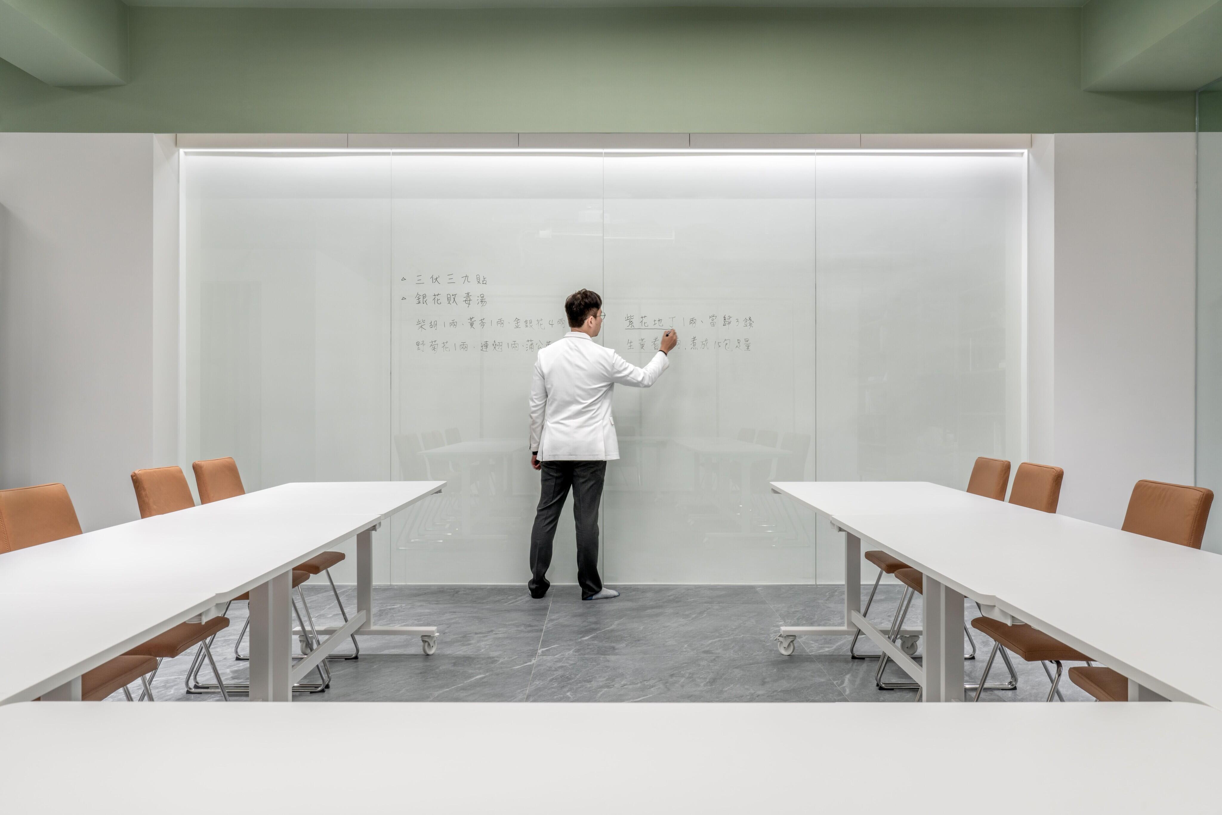 走進至和中醫辦公室，陽光灑落、綠意盎然。苔癬綠天花與漂浮文字牆延續自然氣息，開放書櫃劃分會議與辦公區，是值得參考的辦公室設計案例。